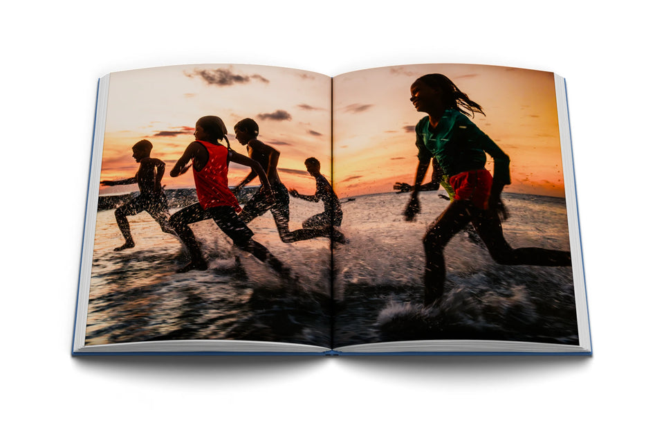 Libro abierto con niños corriendo en el mar al atardecer